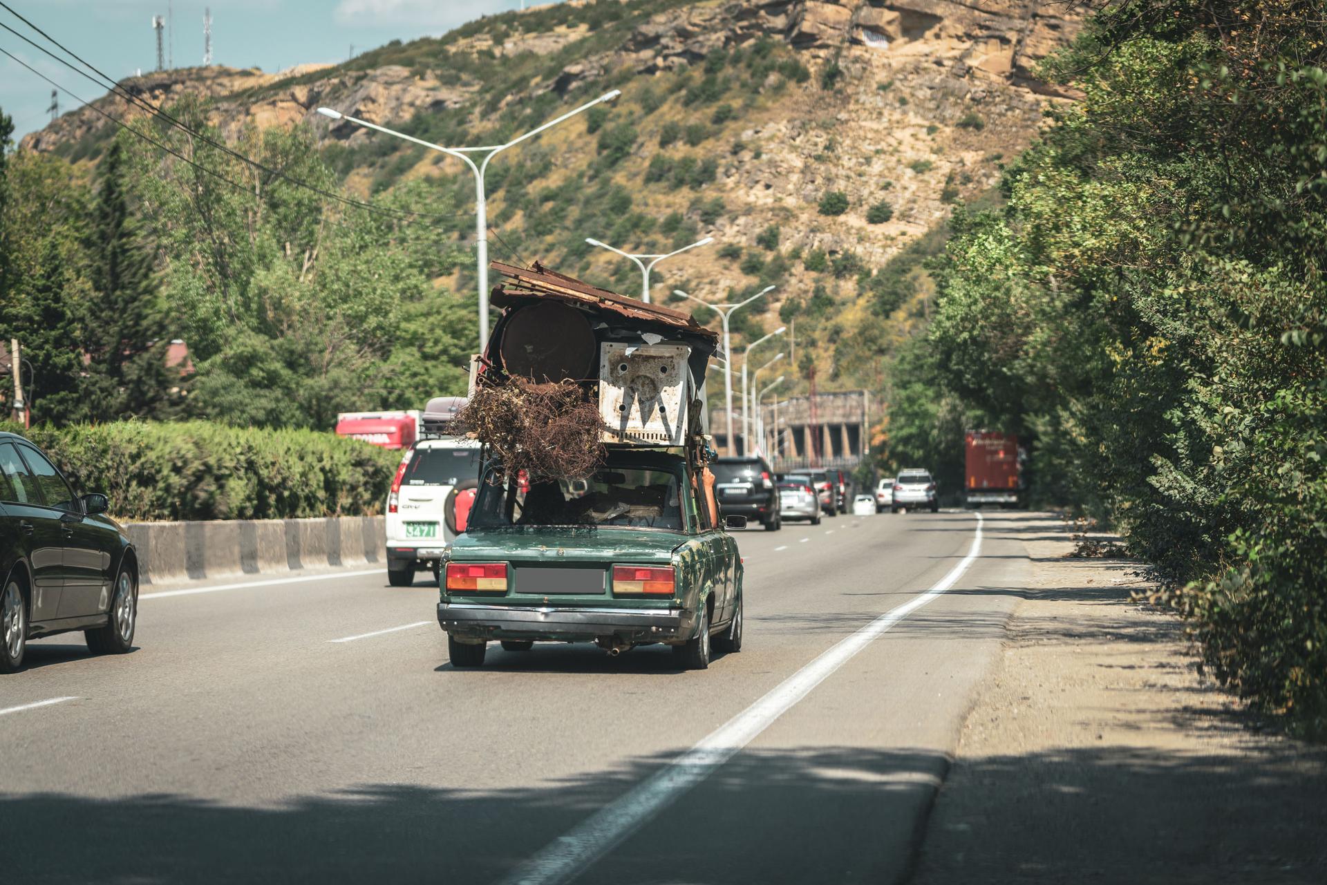 Der Fahrer trägt einen Haufen Schrott auf seinem Auto im Verkehr in Georgien.